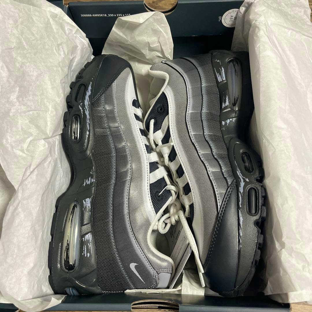 Pair of NIKE Air Muscle 95 QS YGO shoes in the opened box showing gray and black uppers with white laces.