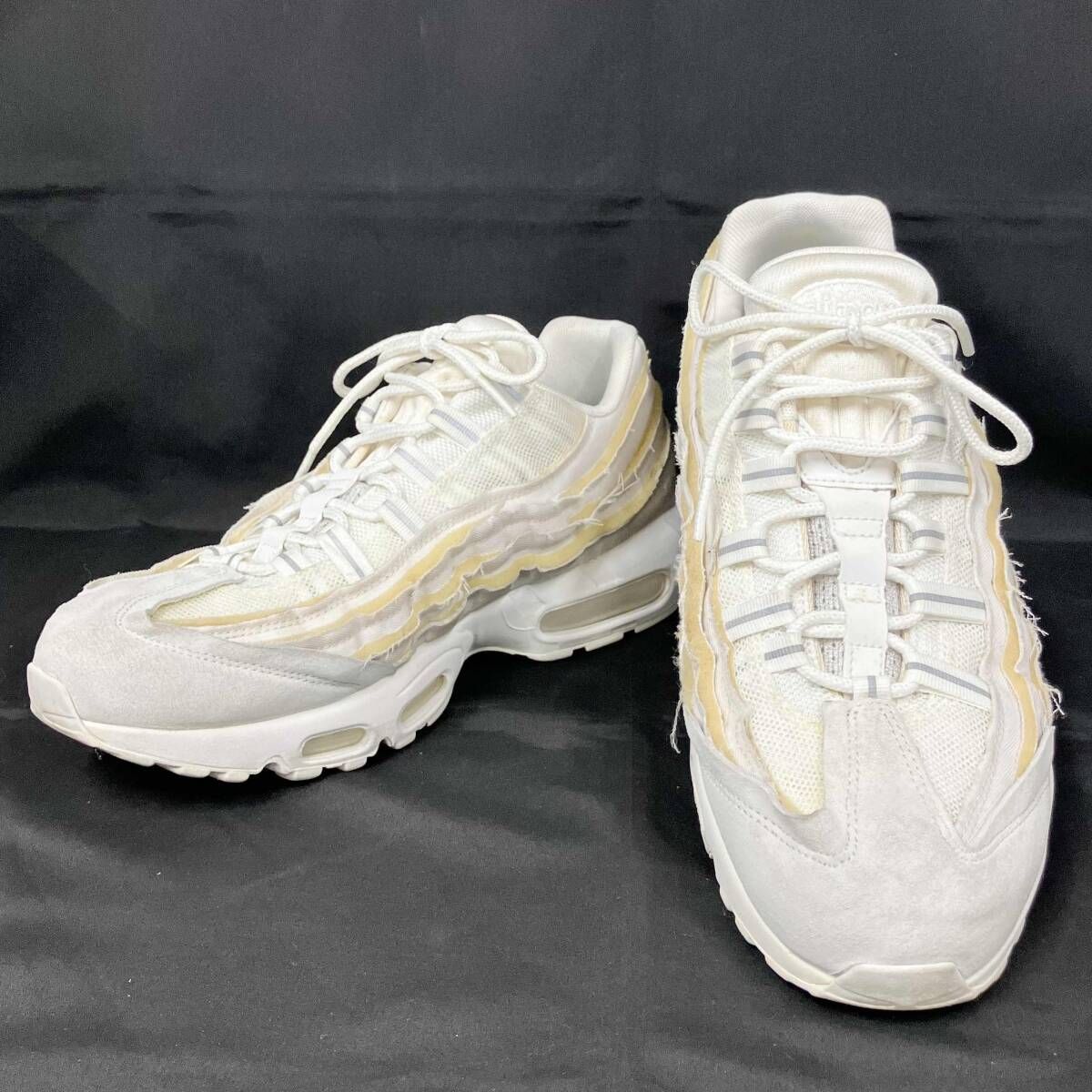 Pair of white NIKE COMME des GARÇONS × Air Max 95 men's sneakers on a black background.