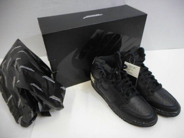 Pair of black Nike × Undercover Dunk High sneakers next to their black shoebox and branded tissue paper.