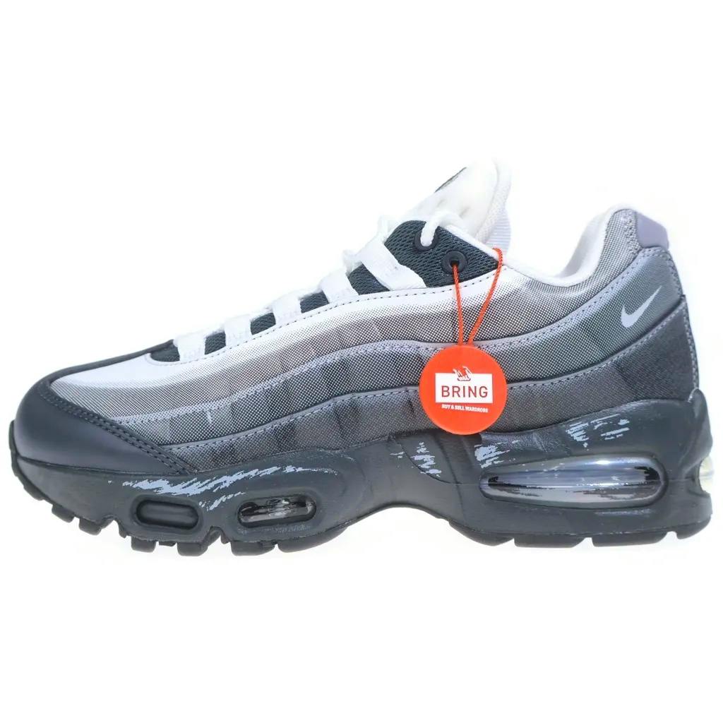 Side view of a grey NIKE Air Max 95 low-cut sneaker with an orange round BRING tag attached.