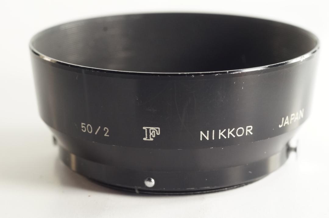 Black Nikkor lens hood marked "50/2", a stylized F, and "JAPAN" sitting on a white background.