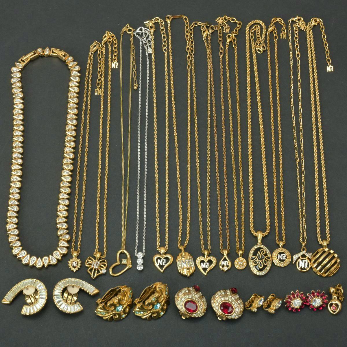 A laid-out selection of gold-tone NINA RICCI and other necklaces and earrings with stone accents arranged on a dark background.