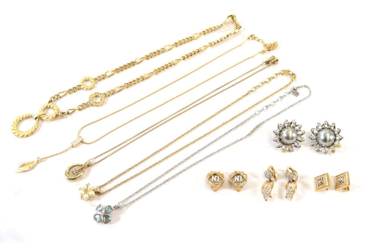 Multiple Nina Ricci necklaces and earrings in gold and silver tones arranged on a white background.