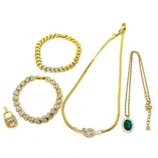Flat lay of gold-tone NINA RICCI jewelry pieces including a necklace, bracelets, and pendants on a white background.