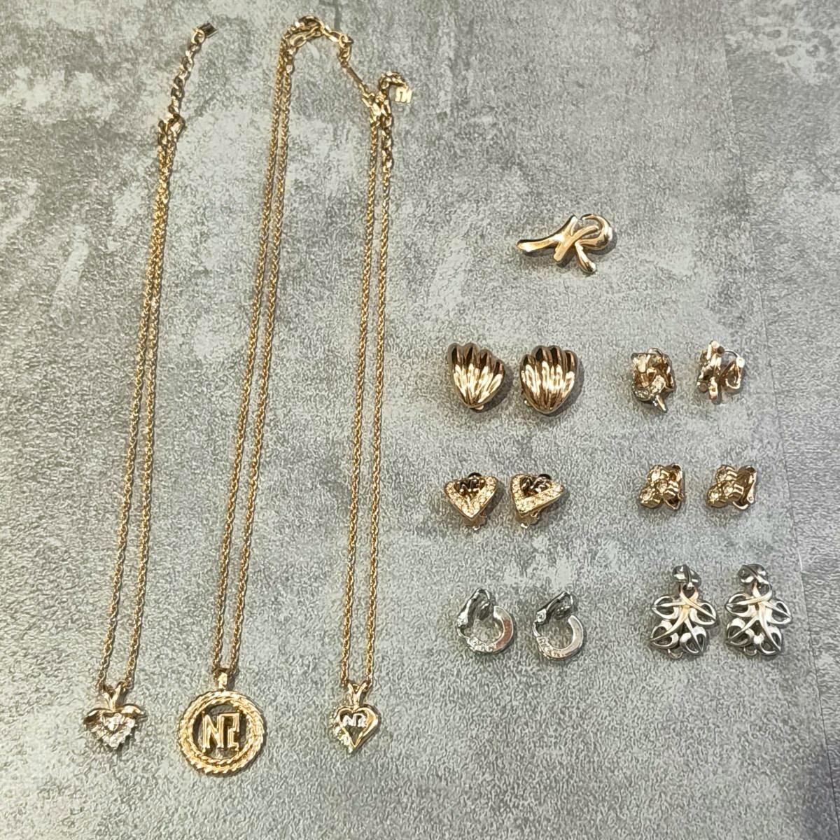 Three gold-tone necklaces and multiple pairs of earrings and brooches arranged on a gray surface.