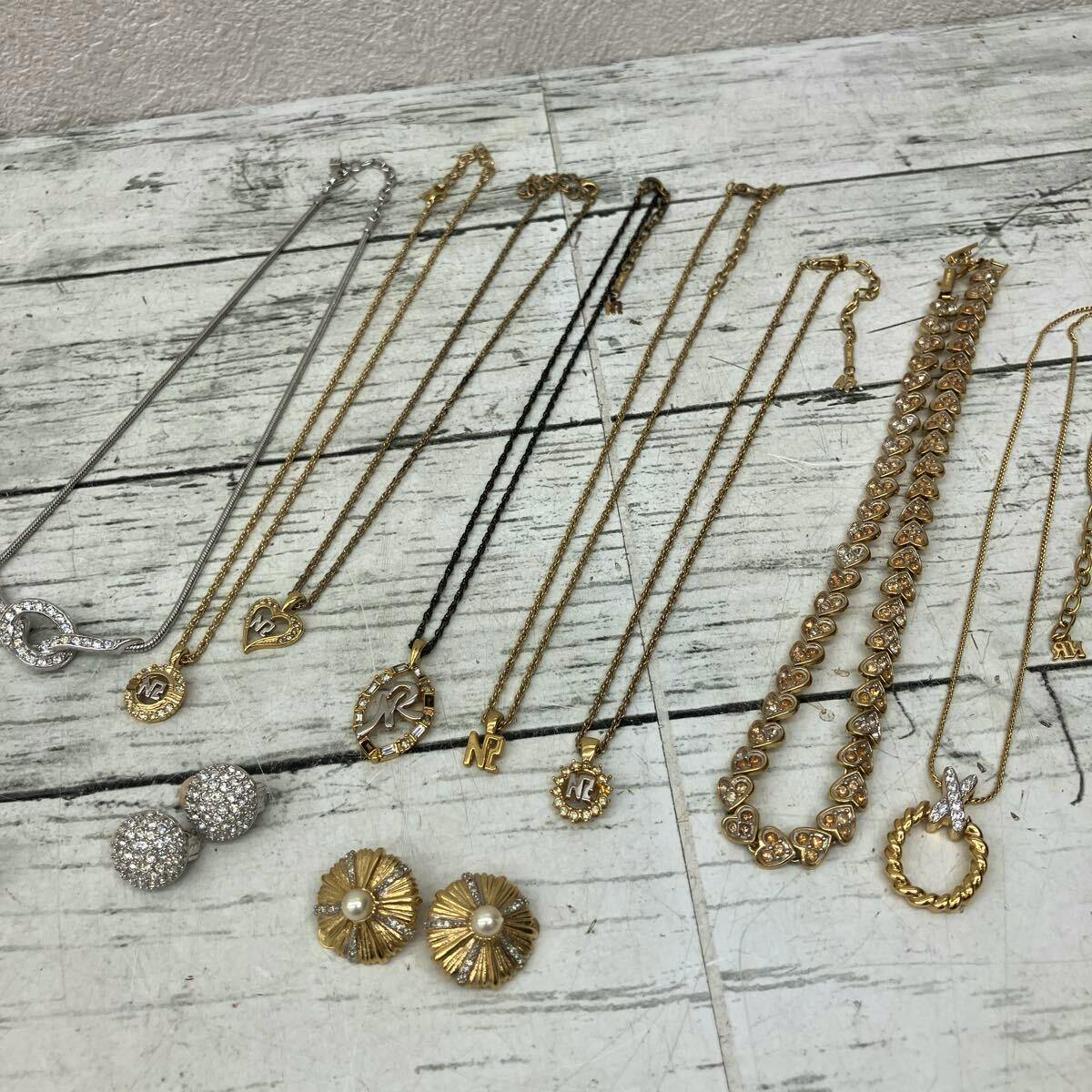 Multiple Nina Ricci necklaces and earrings in gold and silver tones arranged on a light wooden surface.