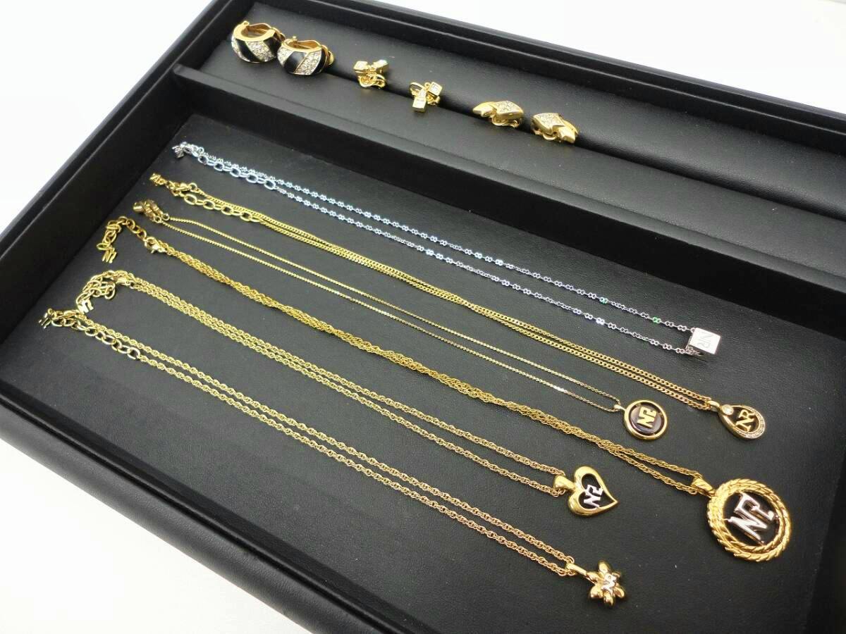 Multiple NINA RICCI necklaces and earrings arranged in a black jewelry tray, showing chains and pendants.