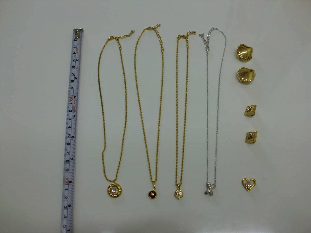 Seven NINA RICCI jewelry pieces (four necklaces, two earrings, one pendant) laid flat on a white surface next to a measuring tape.