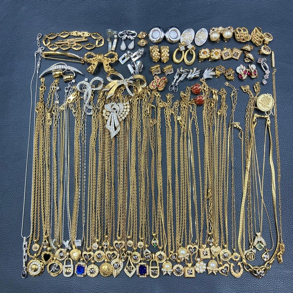 Multiple NINA RICCI gold and silver necklaces with matching earrings and brooches laid flat on a dark background.