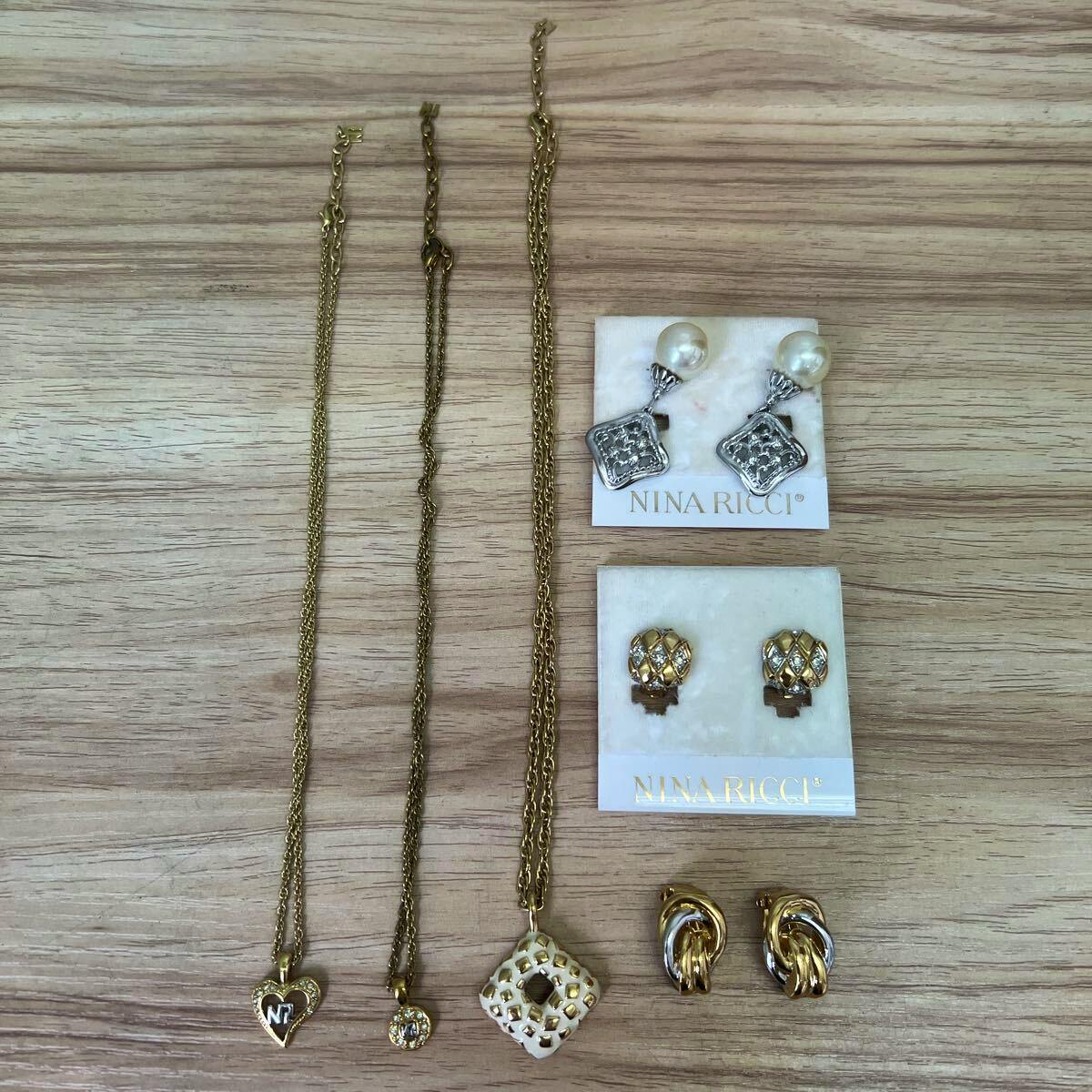 Three gold-colored necklaces and three pairs of gold-tone Nina Ricci earrings displayed on a wooden surface.