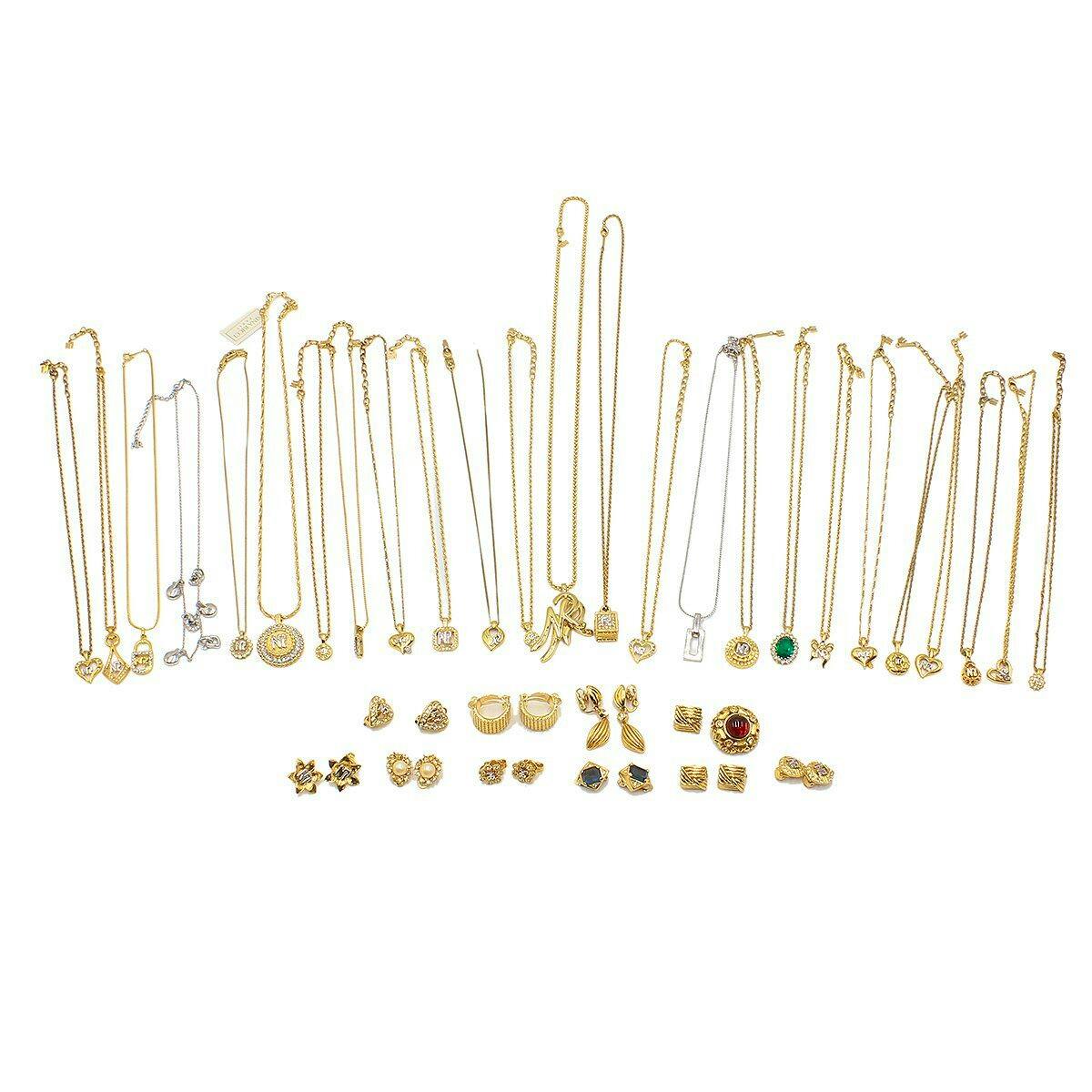 Spread of numerous gold-tone necklaces, pendants, and pairs of earrings displayed on a white background.