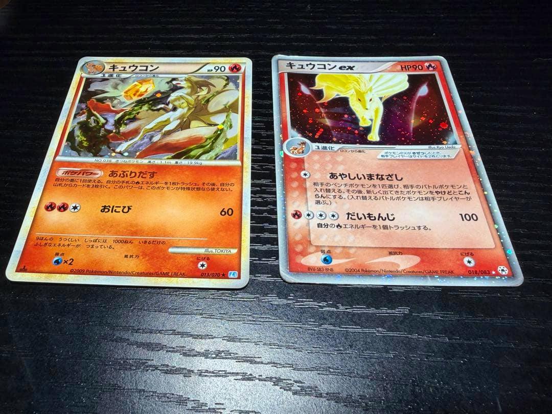 Two Japanese Ninetales Pokémon trading cards (キュウコン and キュコンex) laid side by side on a dark surface.