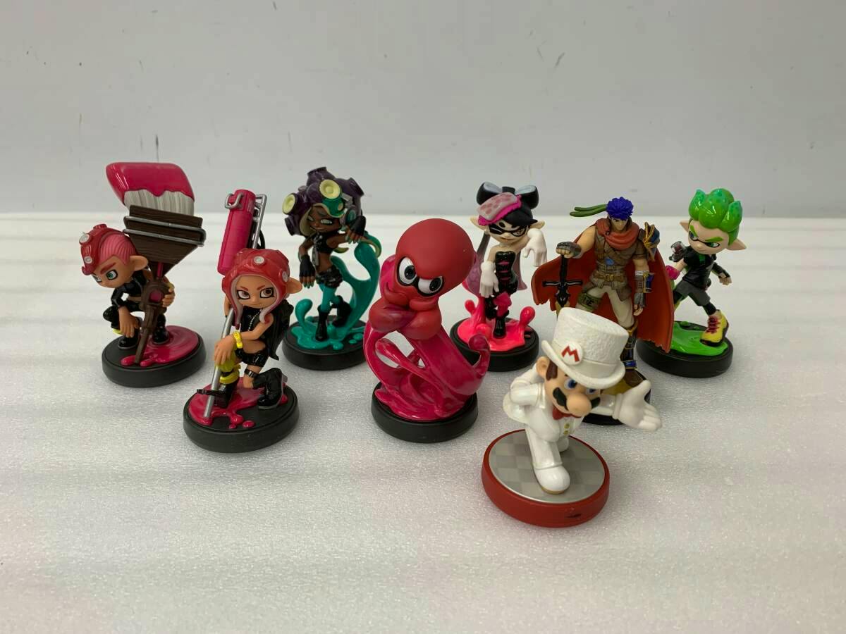 Several amiibo figures on a white surface, including a neon-pink Splatoon octopus amiibo in the center.