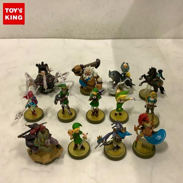 Multiple Nintendo amiibo figures from The Legend of Zelda arranged on a white surface, photographed together showing characters on round bases.