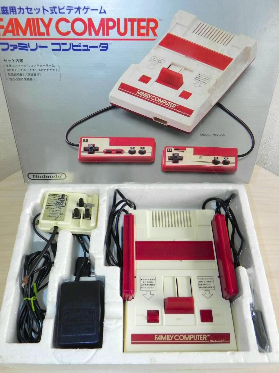 Nintendo Family Computer (Famicom) console with two controllers and power adapter arranged in the original styrofoam tray with the box artwork visible behind.