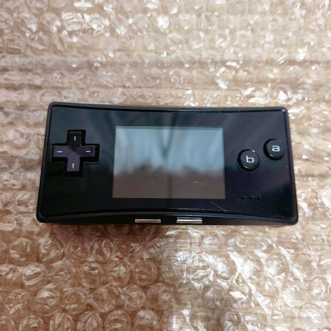 Front of a black Nintendo Game Boy Micro showing the screen, directional pad, and A/B buttons placed on bubble wrap.