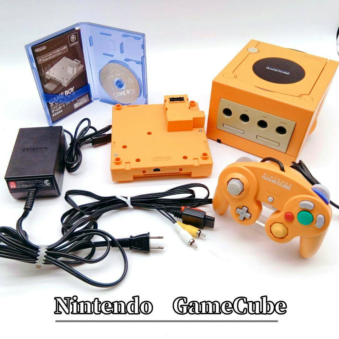 Orange Nintendo GameCube console with the Game Boy Player, orange controller, power adapter, and AV cables on a white background.