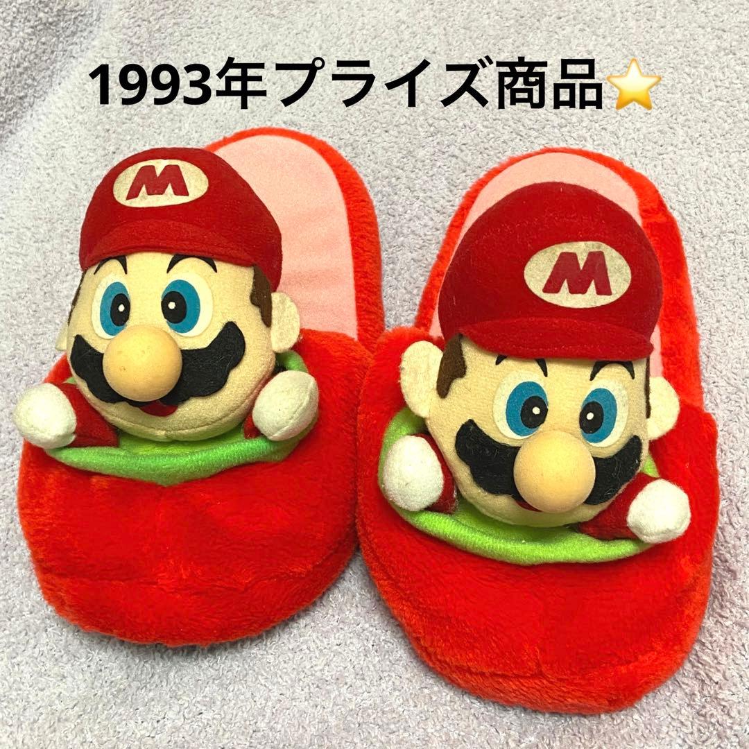 A pair of red Nintendo Mario plush slippers photographed from above on a light towel background with Japanese text overlaid.