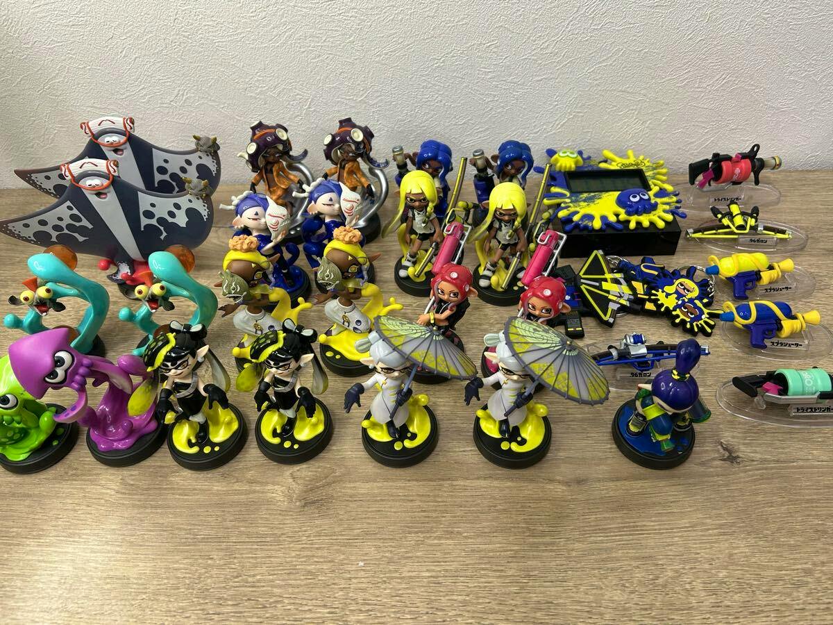 Multiple Splatoon amiibo figures and accessory pieces arranged on a wooden surface.