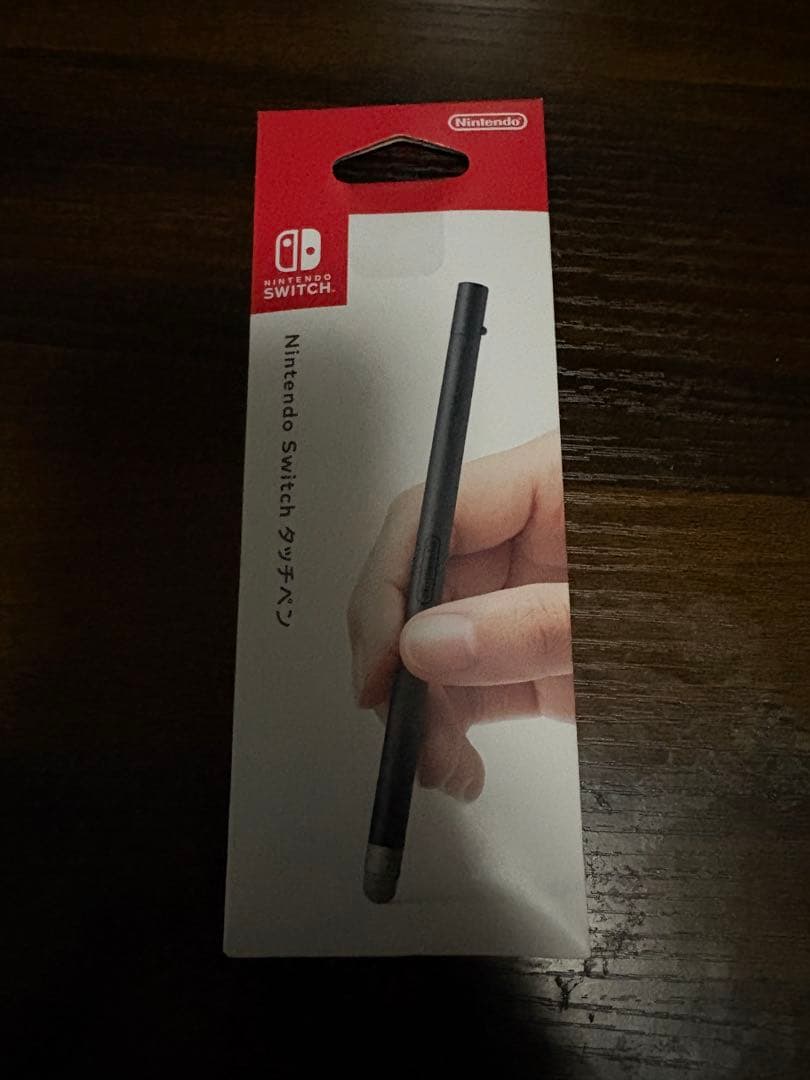 Front of Nintendo Switch stylus packaging showing a hand holding a black stylus on the box.