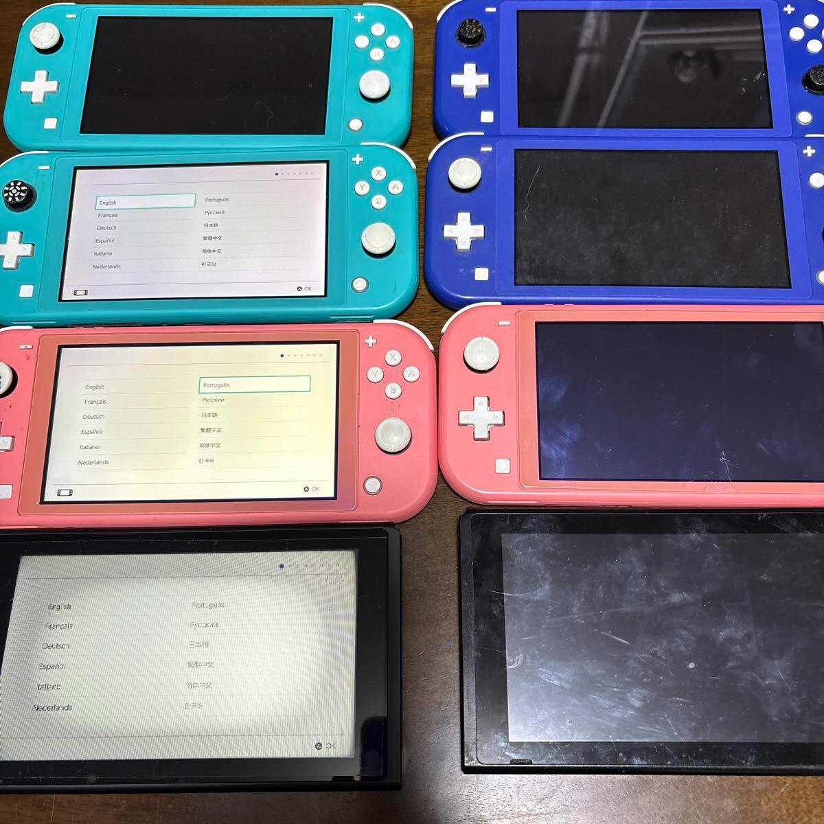 A group of Nintendo Switch Lite handheld consoles in several colors arranged on a table showing their front screens and controls.