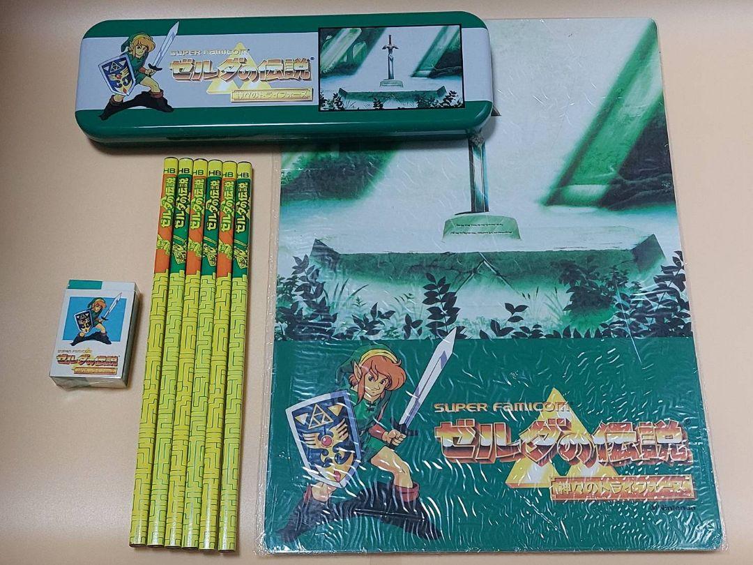Zelda-themed stationery set including a metal pencil tin, a folder, an eraser, and multiple yellow pencils.