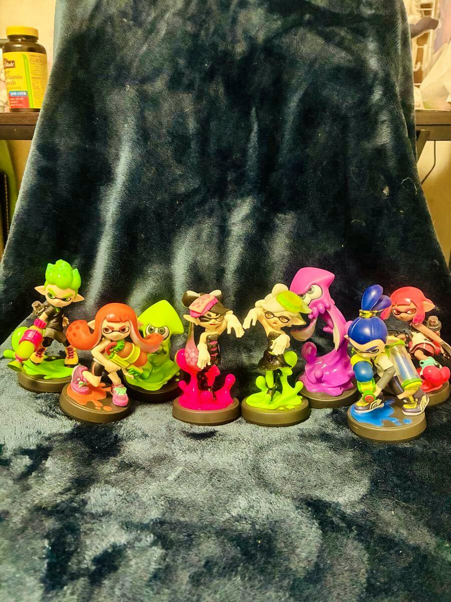 Several Splatoon amiibo figures arranged in a row on a dark fabric background.