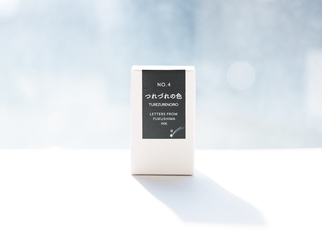 White rectangular box of NO.4 つれづれの色 fountain pen ink (20ml) with a black label, photographed against a soft blue bokeh background.