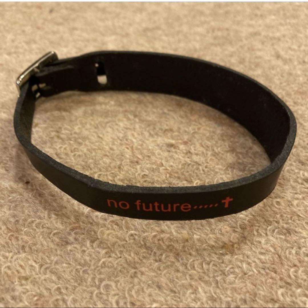 Black leather collar with red "no future......†" text placed on beige carpet.