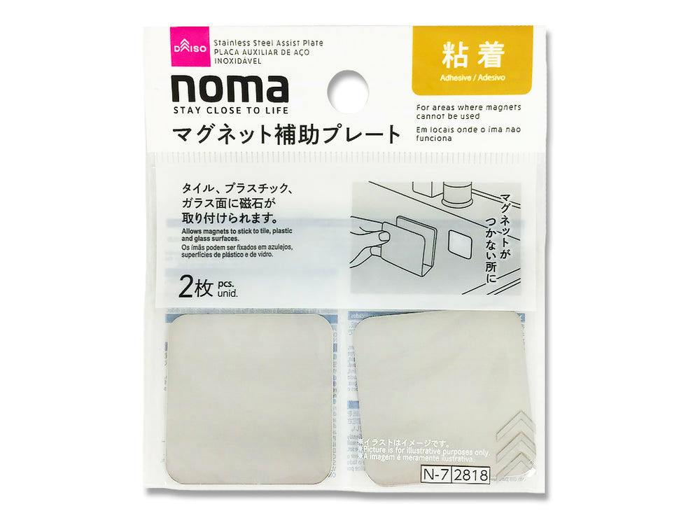 Retail packaging containing two square adhesive magnet-assist plates labeled "noma".