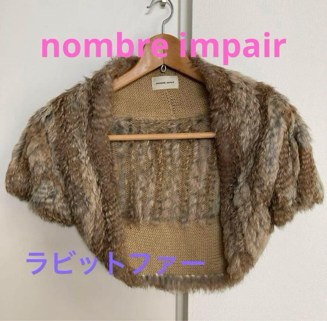 Brown rabbit-fur bolero (shawl) hanging on a wooden hanger against a white wall with brand text overlay.