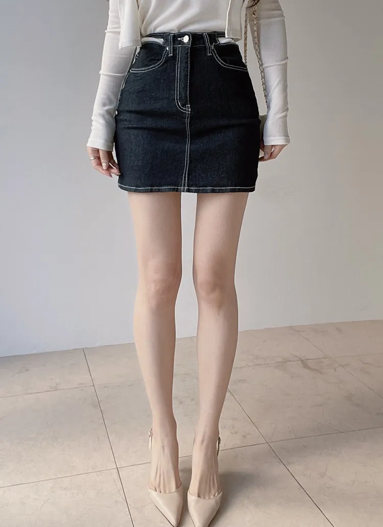 Front view of a model wearing the non-wash stitch strap mini skirt in a dark fabric, showing the skirt's front, waist, and contrast stitching.
