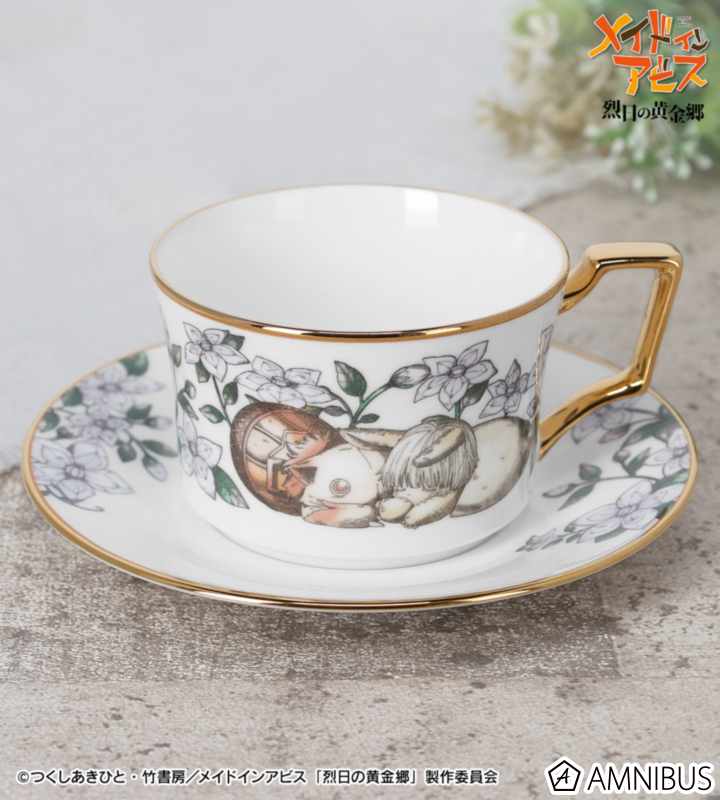 A porcelain cup and matching saucer set with floral and character illustration and gold trim and a gold handle.