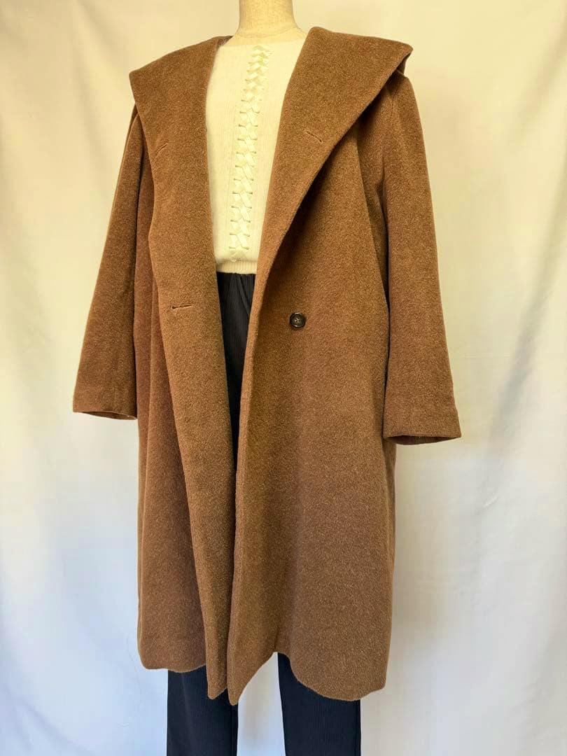A brown wool women's hooded coat displayed on a mannequin over a cream sweater and dark trousers.
