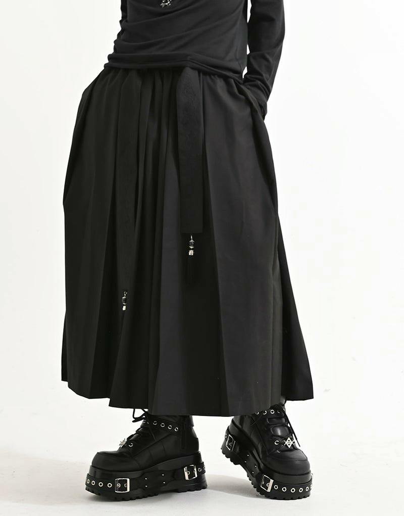 Model wearing black NOVESSEL hakama wide pants showing pleats, side pockets, and decorative hanging cords, paired with platform boots.