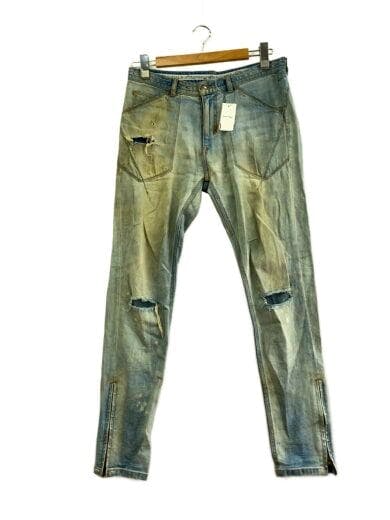 Front view of distressed indigo men's denim jeans with knee rips and ankle zippers hanging on a hanger.
