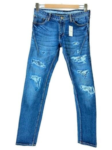Front view of blue distressed men's jeans hanging on a wooden hanger with a visible tag.