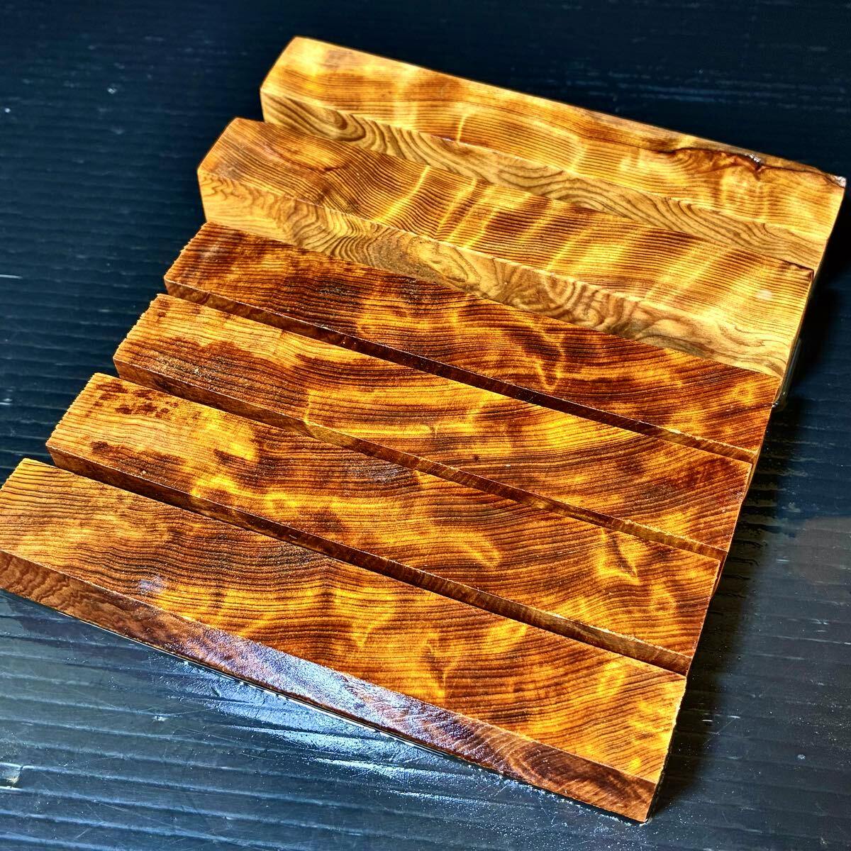 A set of rectangular Yakusugi pen blank wood blocks with vivid tiger-like flame grain patterns arranged on a dark surface.