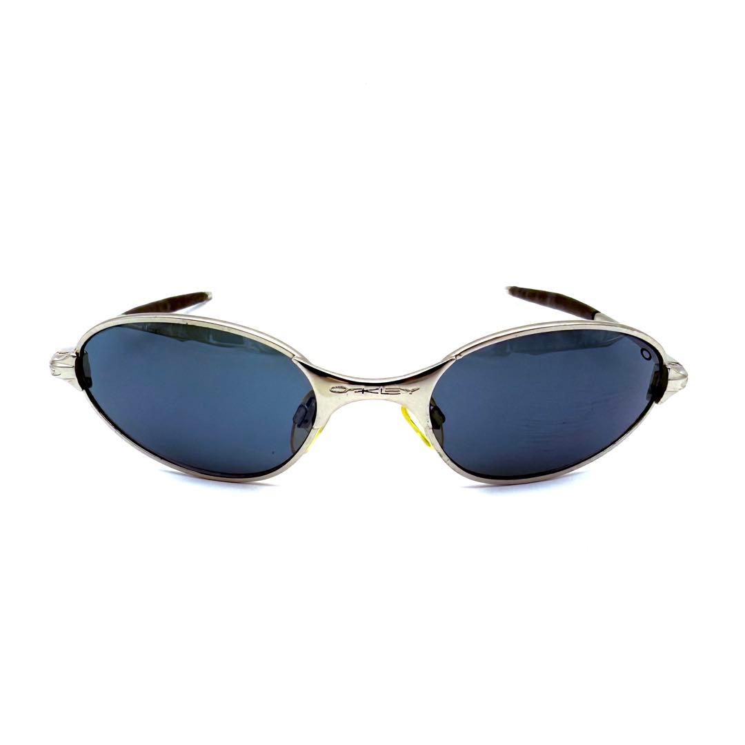 Front view of Oakley C-Wire X-Metal oval sunglasses with silver frame and dark lenses on a white background.