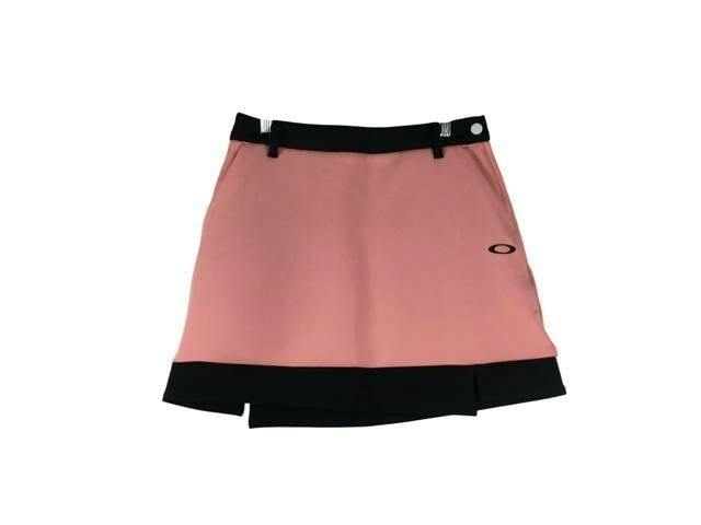 Pink OAKLEY golf skirt with a black waistband and hem on a white background.