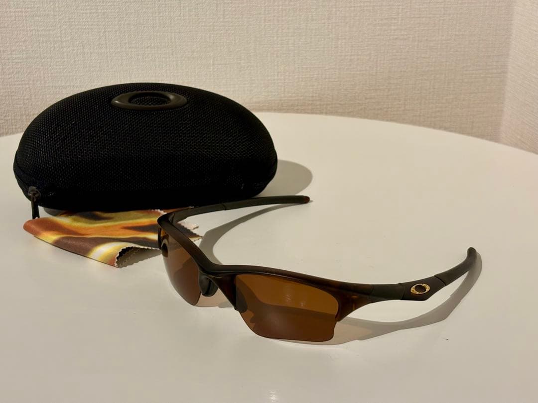 Oakley Half Jacket 1.0 polarized sunglasses displayed with a hard case and cleaning cloth on a white surface.