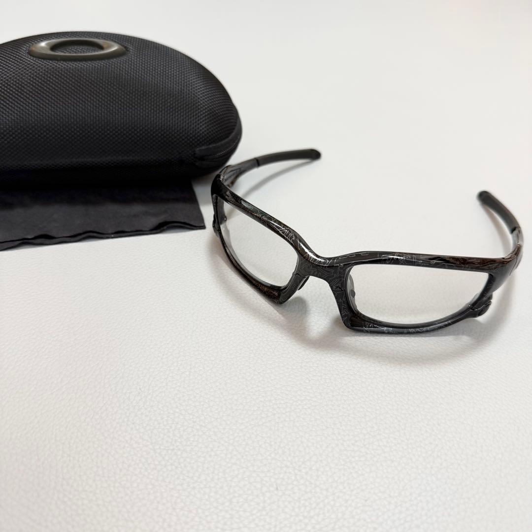 OAKLEY SPLIT JACKET clear-lens sunglasses (oo9138) with a hard case and cleaning cloth on a white surface.