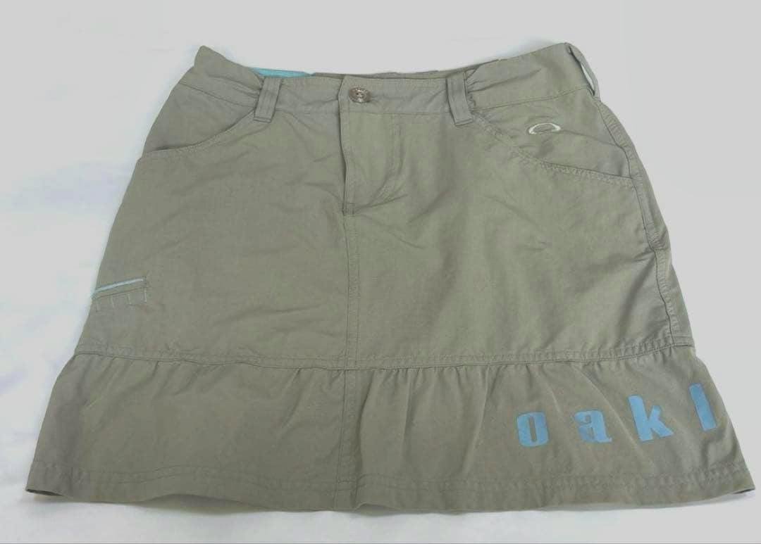Light gray Oakley women's golf skirt laid flat showing front pockets and logo.