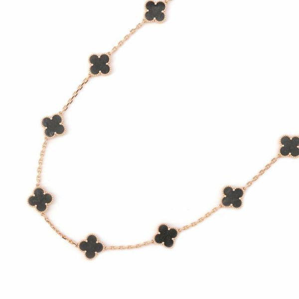 Gold necklace with multiple black obsidian clover-shaped charms laid on a white background.