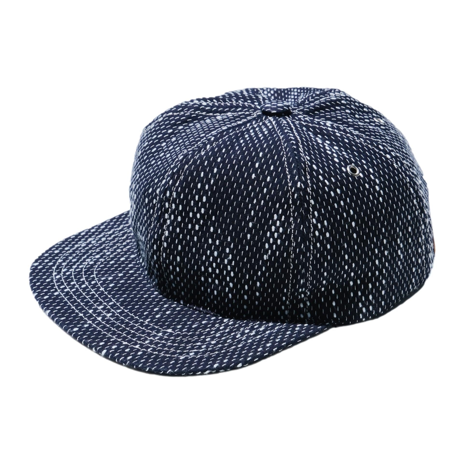 Natural indigo six-panel sashiko cotton baseball cap with white running-stitch pattern shown at a three-quarter angle.