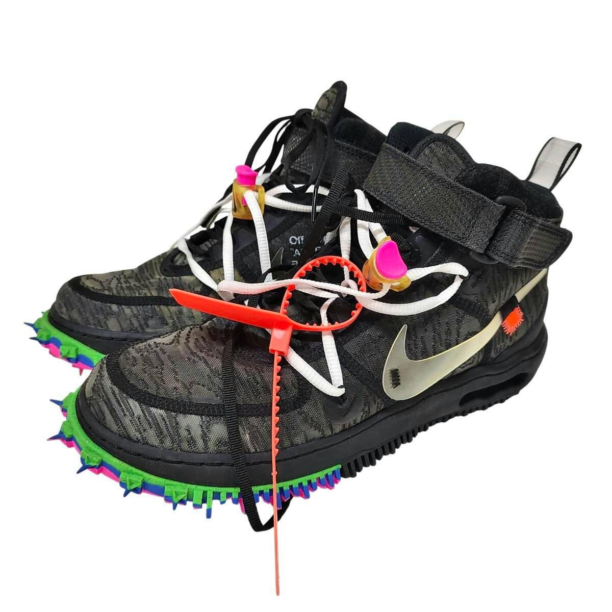Pair of black OFF-WHITE × Nike Air Force 1 Mid sneakers with white laces, silver Swoosh, ankle strap, orange zip tie, and colorful spiked soles.