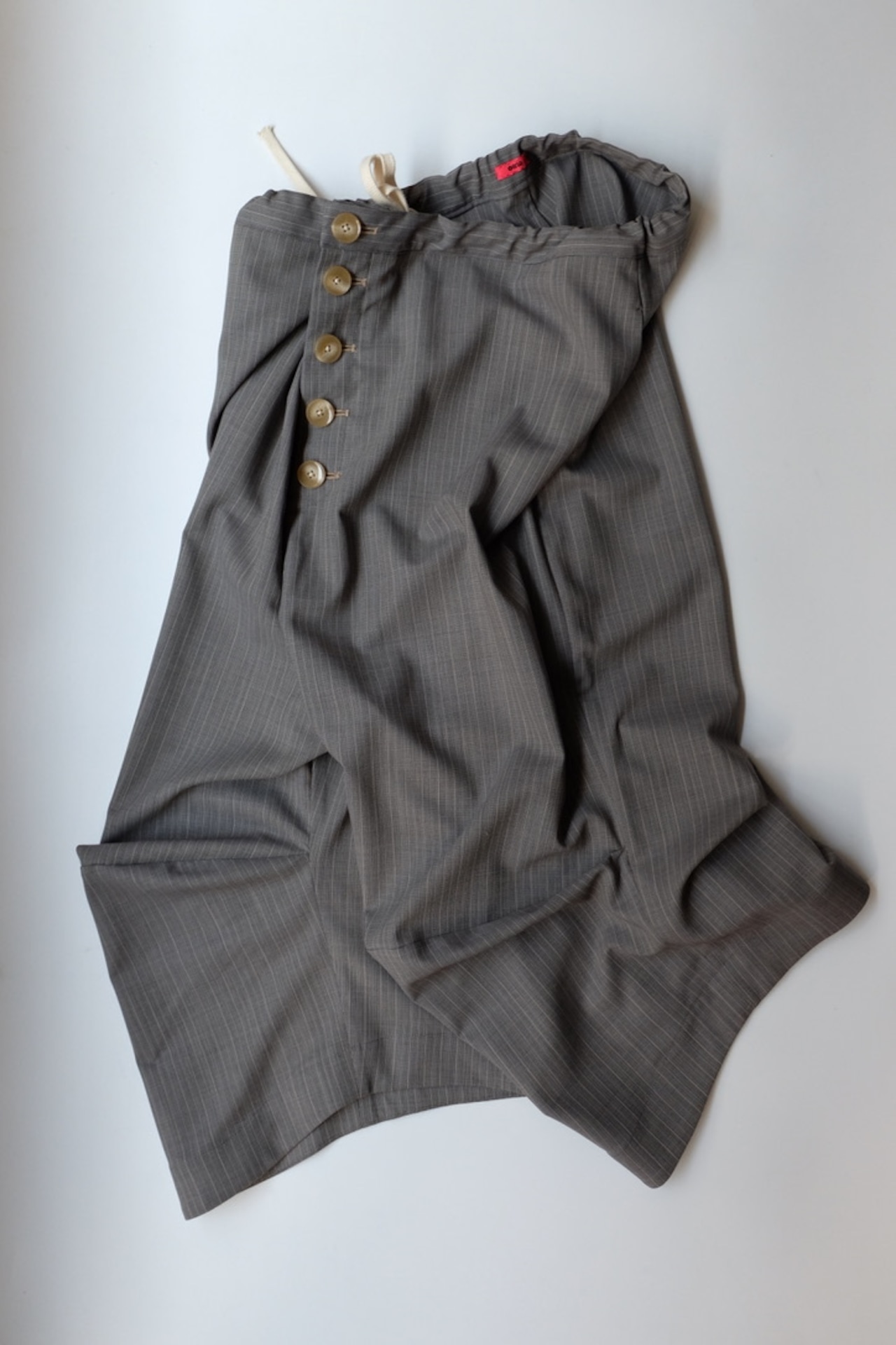 Gray pinstriped women's wool shorts with a row of front buttons and a drawstring waistband laid flat on a white background.