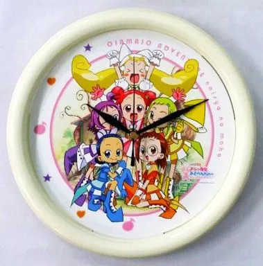 Round white wall clock with printed illustration of the five Ojamajo characters and visible clock hands.