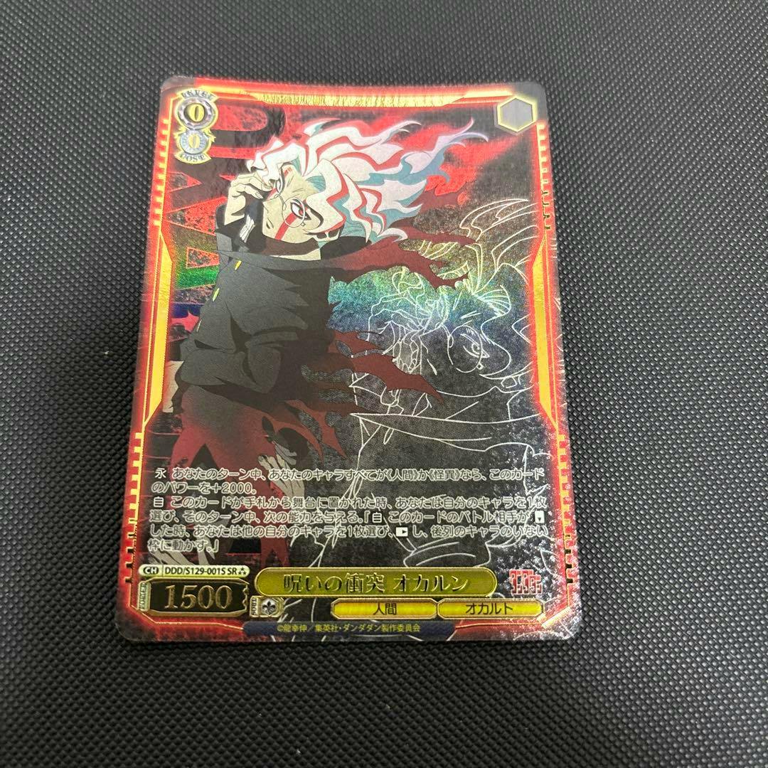 Front of the trading card '呪いの衝突 オカルン SR' showing the character artwork, Japanese text, and foil holographic details.