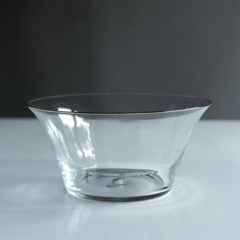 Clear glass soribachi-style bowl with flared sides and a thin gold rim on a neutral surface.